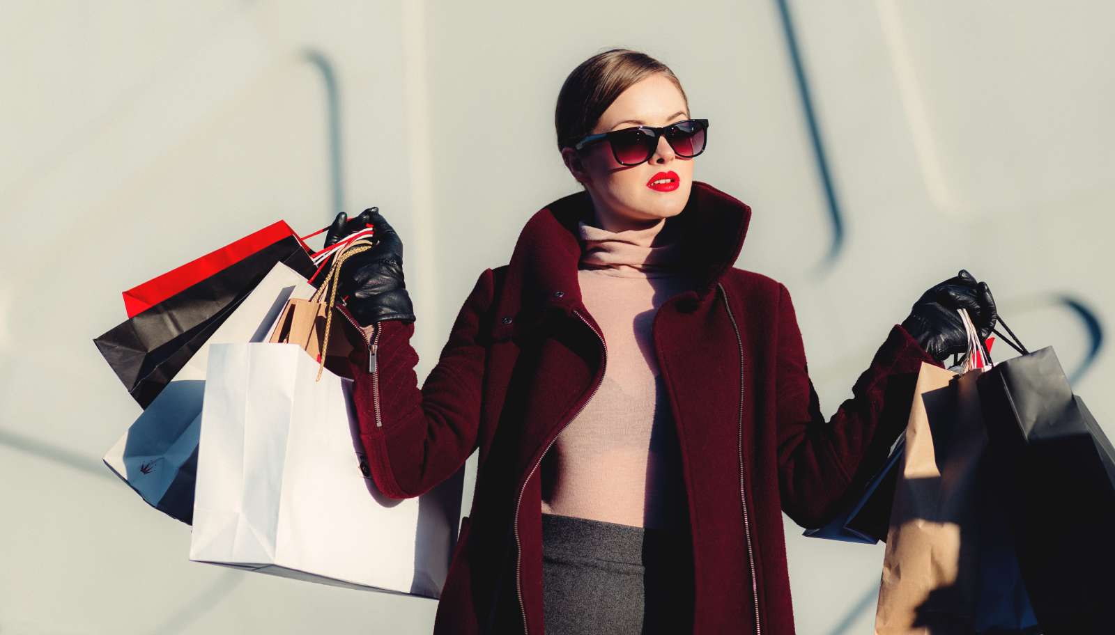 Eine gestylte Frau mit Einkaufstaschen links und rechts